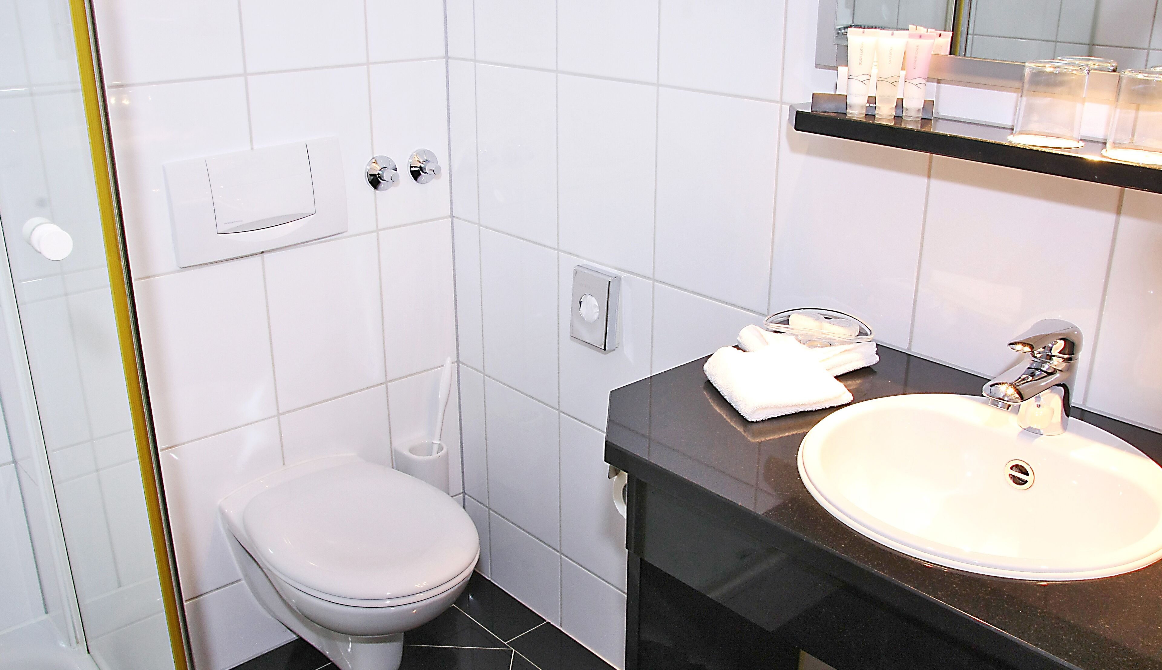 A bathroom with a toilet, sink, and mirror.