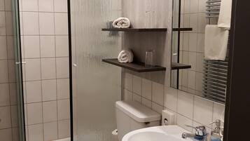 A bathroom with a toilet, sink, and a glass shower enclosure.