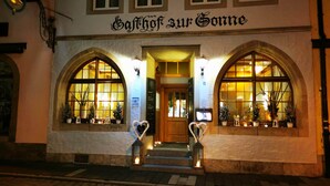 Un edificio con ventanas de arco y un letrero que dice "Gasthof zur Sonne".