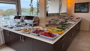 A buffet setup with various food items, a grill, and a view of trees through the window. - Sude Konak Hotel - Special class (Istanbul)