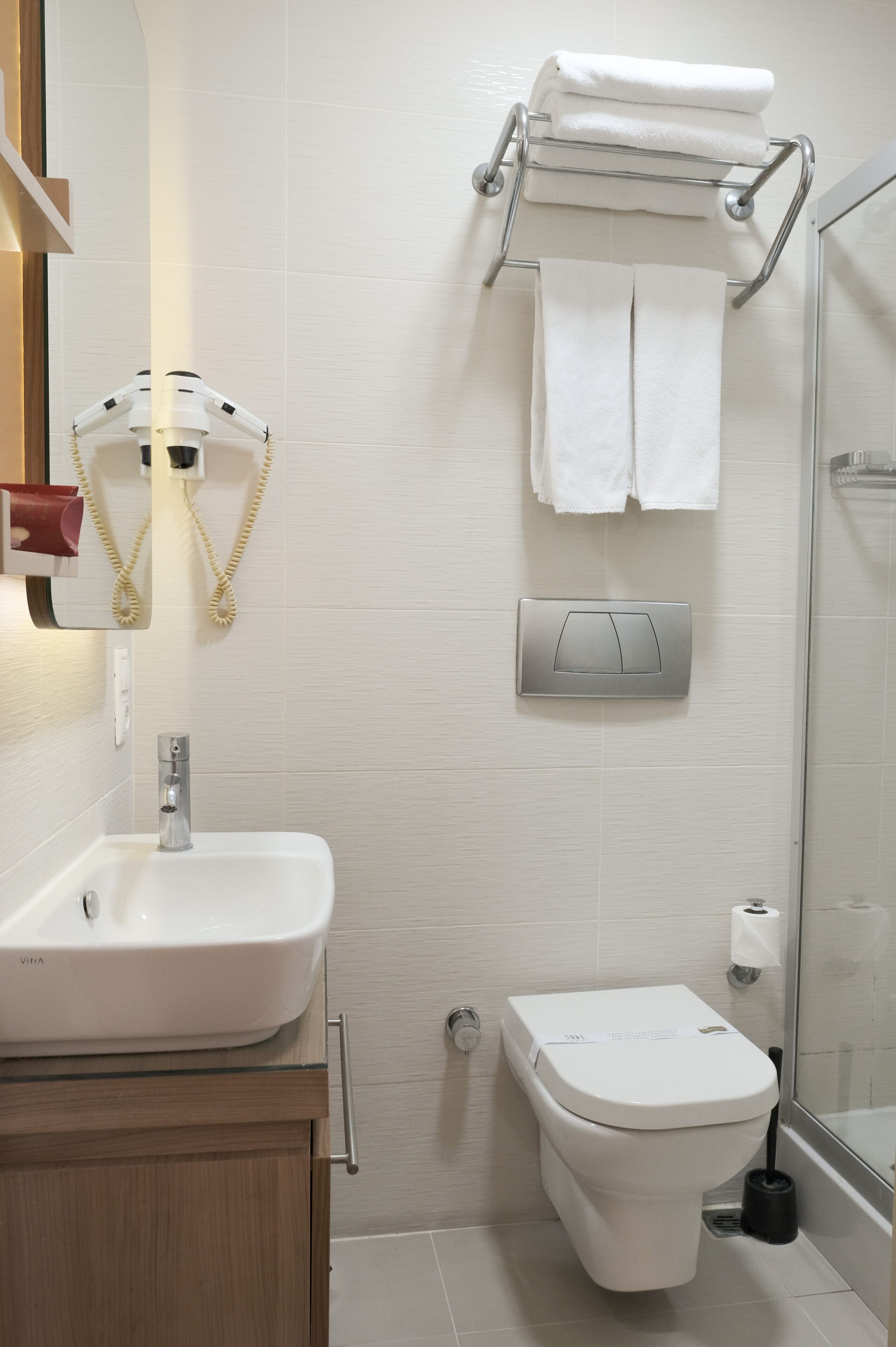A modern bathroom with a white sink, toilet, and glass shower enclosure.