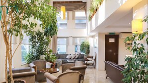 A spacious lobby with a high ceiling, a seating area with sofas and armchairs, and multiple potted plants. - Sude Konak Hotel - Special class (Istanbul)