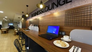 A business lounge with a wooden reception desk, a laptop, a plate of food, and a cup of coffee. - Asal Hotel (Ankara)