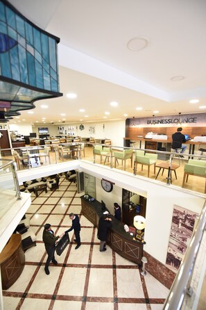 Een hotellobby met een business lounge, een receptiebalie en een klok aan de muur.