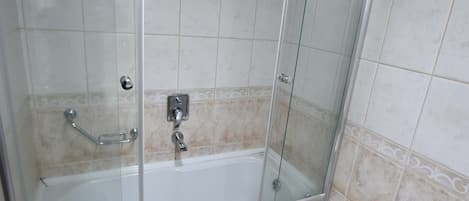 Un baño con ducha acristalada, bañera blanca y un inodoro.