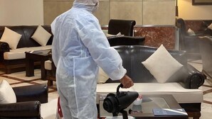 A person in a white protective suit operating a steam cleaner in a hotel lobby with leather sofas and a marble floor. - Asal Hotel (Ankara)