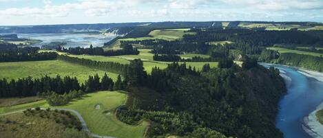A golf course with a river and forested areas.