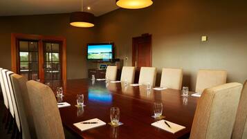 A conference room with a long table, chairs, a television, and a door.
