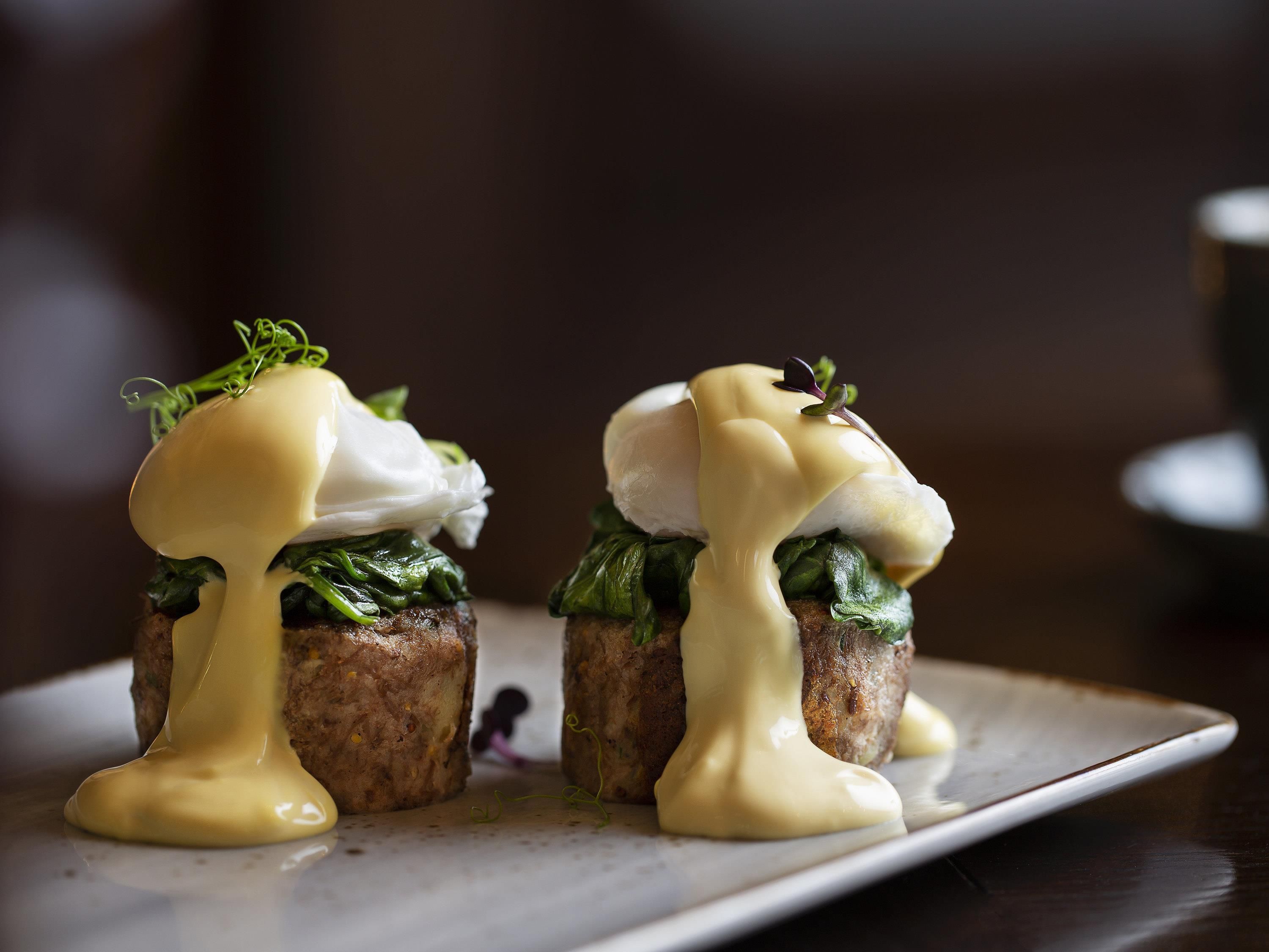 Deux assiettes contenant des œufs pochés et nappés de sauce hollandaise.
