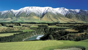 A golf course with a river, forested areas, and snow-capped mountains in the background. - Fable Terrace Downs Resort by Mgallery (Windwhistle)