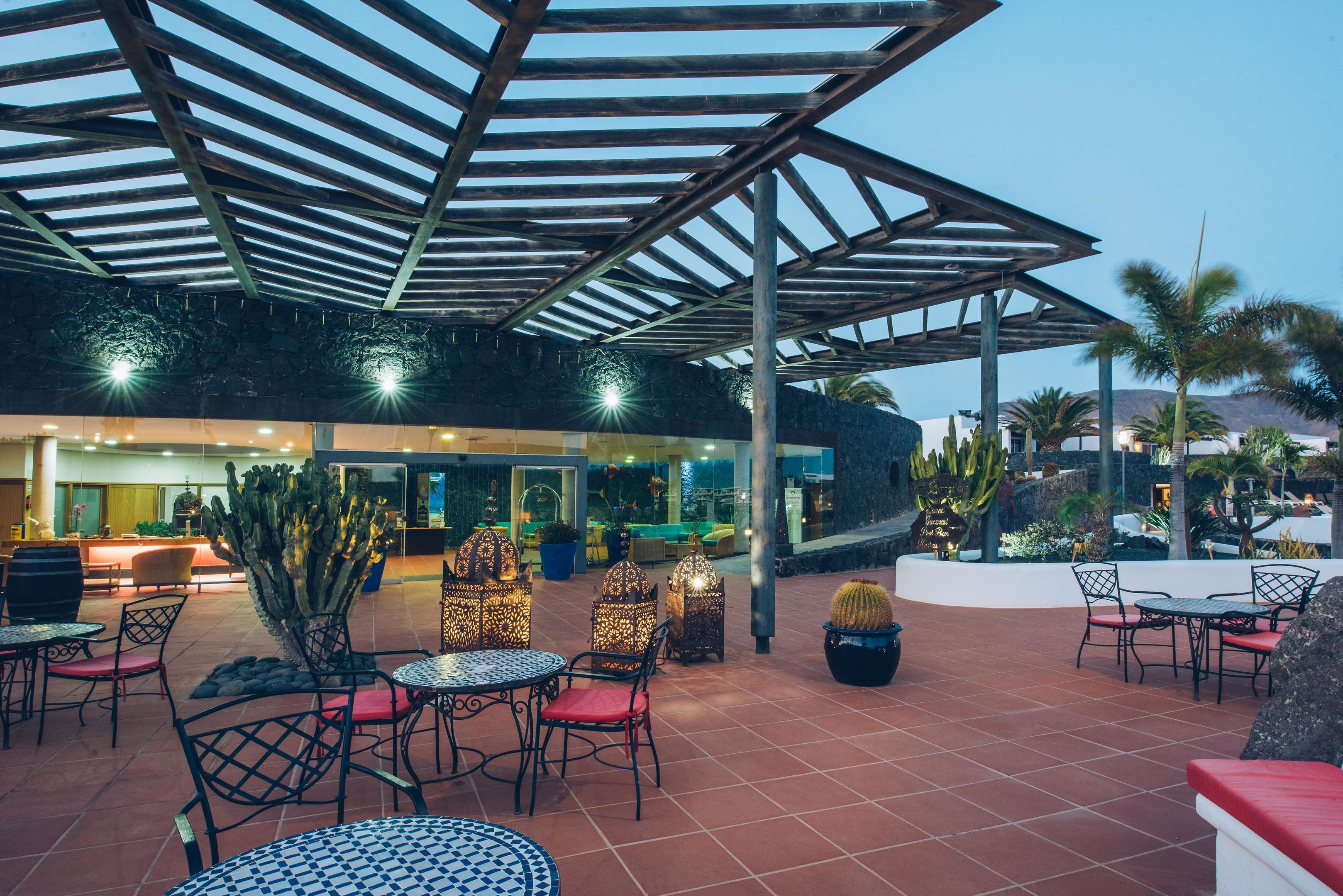 An outdoor patio area with tables and chairs, a covered seating area, and a reception desk.
