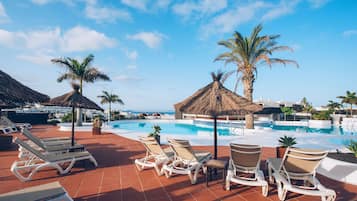 Una piscina al aire libre, sombrillas, sillones reclinables de piscina