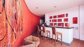 Un área de bar moderna con una pared de acento roja, varias botellas de licor a la vista y un techo curvo.