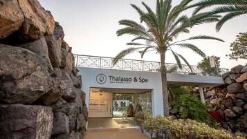 La entrada al Thalasso & Spa, con un muro de piedra y palmeras.