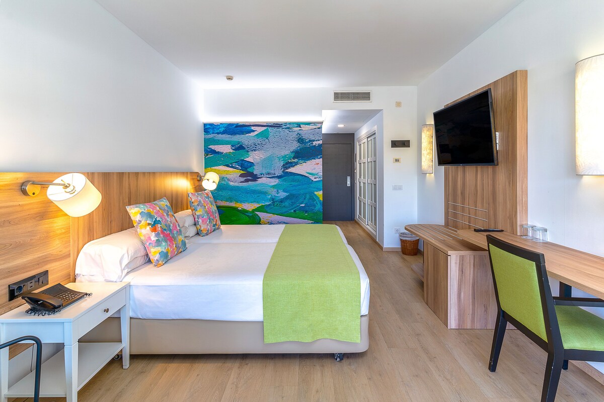 Une chambre d’hôtel moderne équipée d’un lit, d’un bureau, d’une chaise et d’un téléviseur.