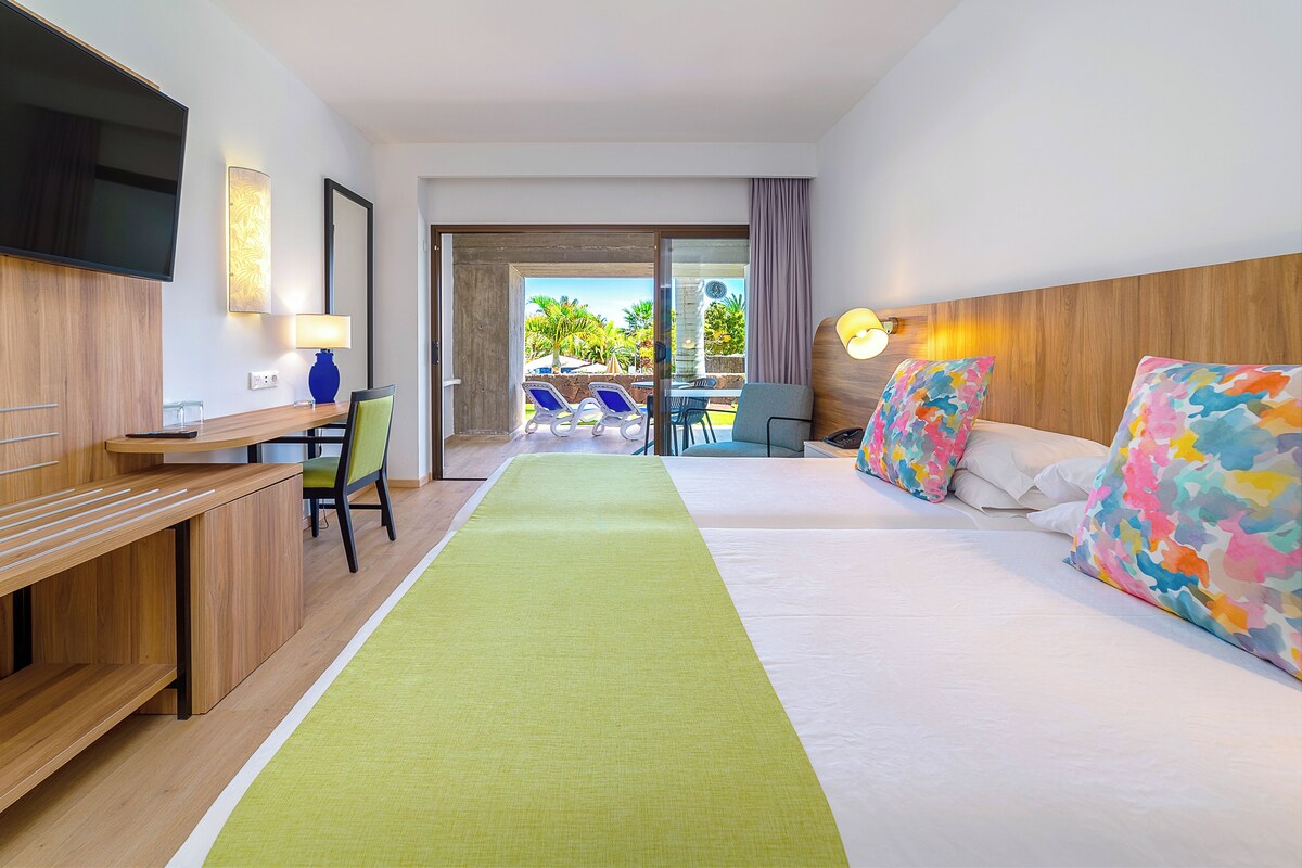 Une chambre d’h ôtel équipée d’un lit, d’un bureau, d’une chaise, d’une télévision et offrant une vue sur l’extérieur.