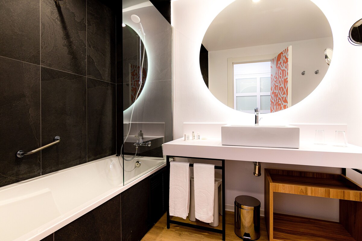 Ein modernes Badezimmer mit Badewanne, Waschbecken und Spiegel.