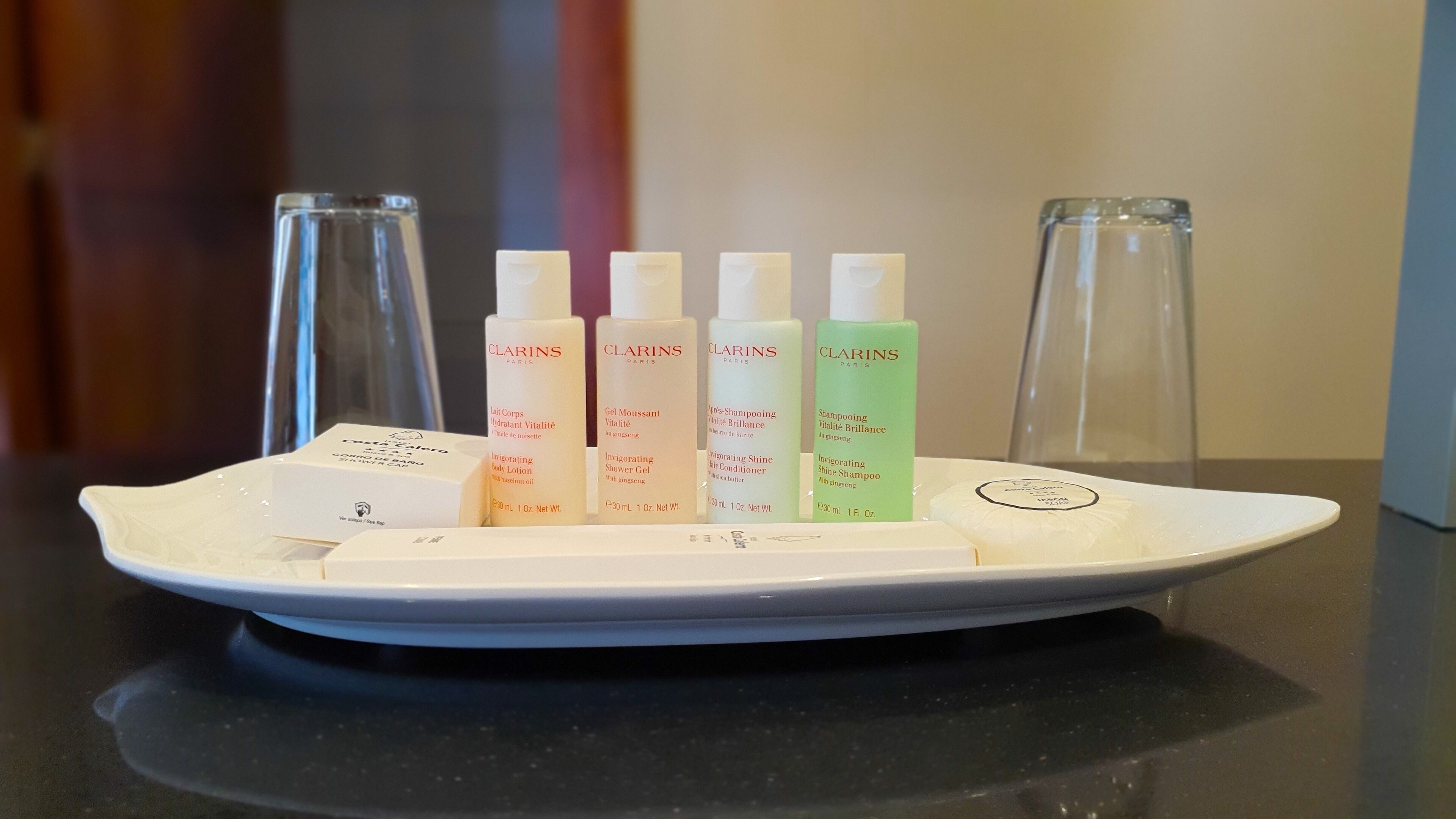 A white tray with five Clarins Paris skincare products and a white box on a black countertop.