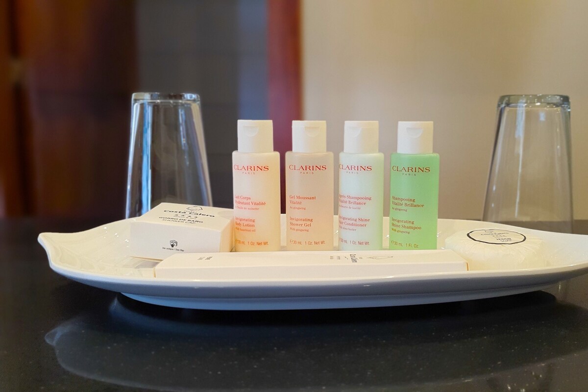 Un plateau blanc contenant cinq produits de soins de la peau de la marque Clarins Paris, ainsi qu’une boîte blanche, le tout posé sur un comptoir noir.