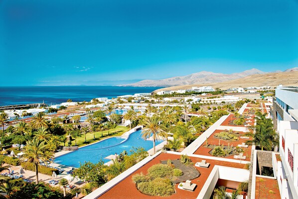 Un resort con piscina, palmeras y vista al océano.