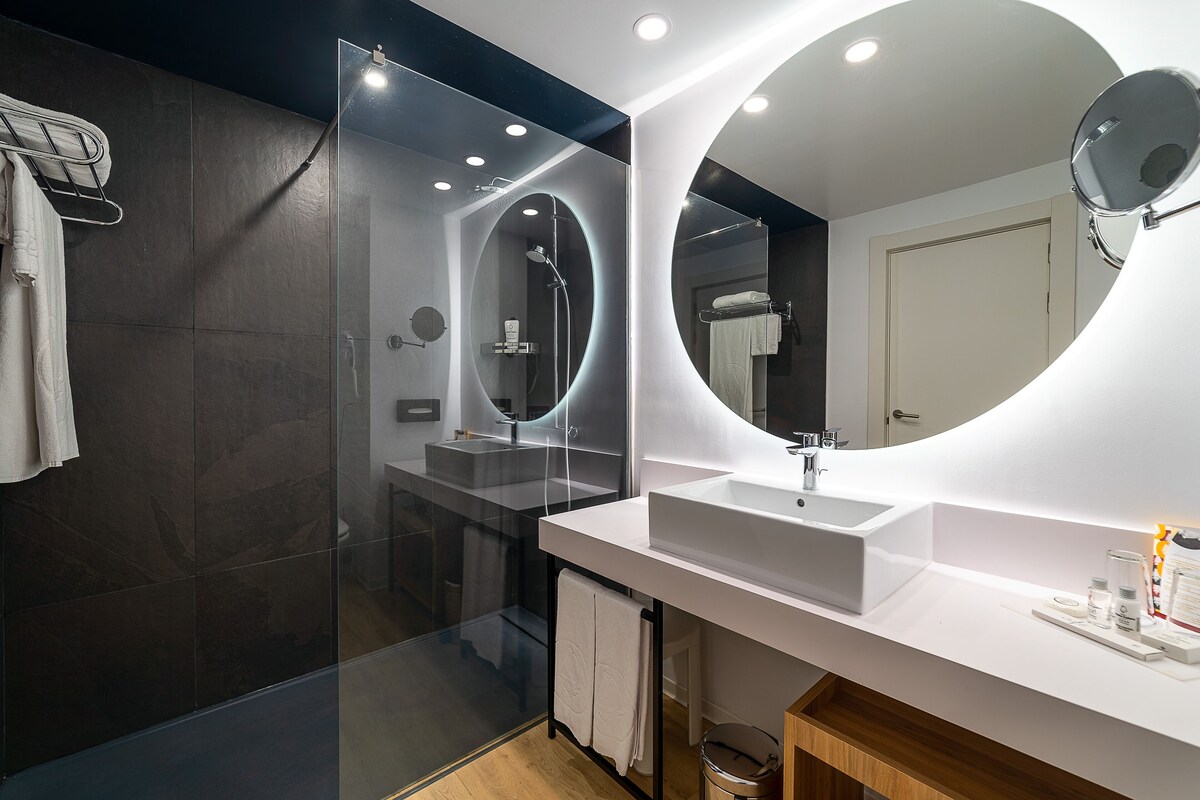 Une salle de bain moderne avec une douche à parois de verre, un meuble-lavabo blanc et un grand miroir.