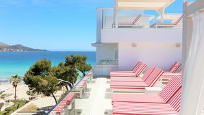 A modern hotel with a balcony overlooking a beach, featuring striped lounge chairs and a clear view of the sea. - Iberostar Waves Alcudia Park (Muro)