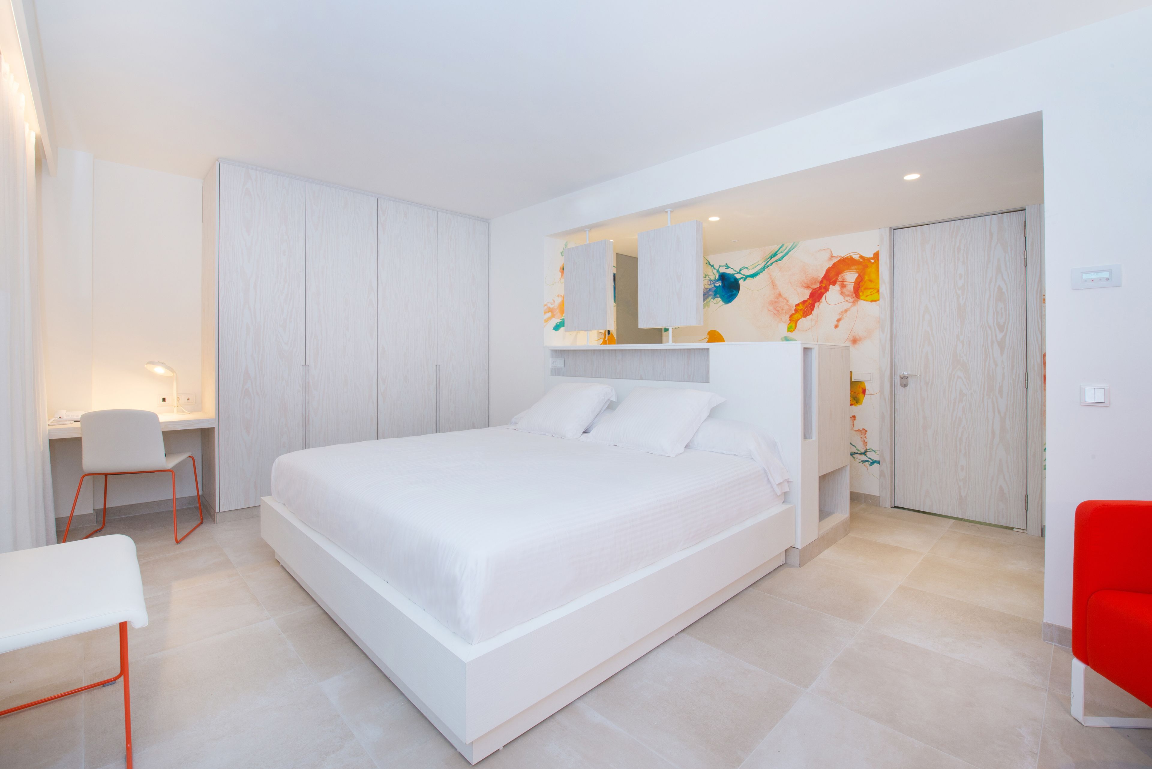 Un dormitorio moderno con una cama grande, un escritorio y una silla.