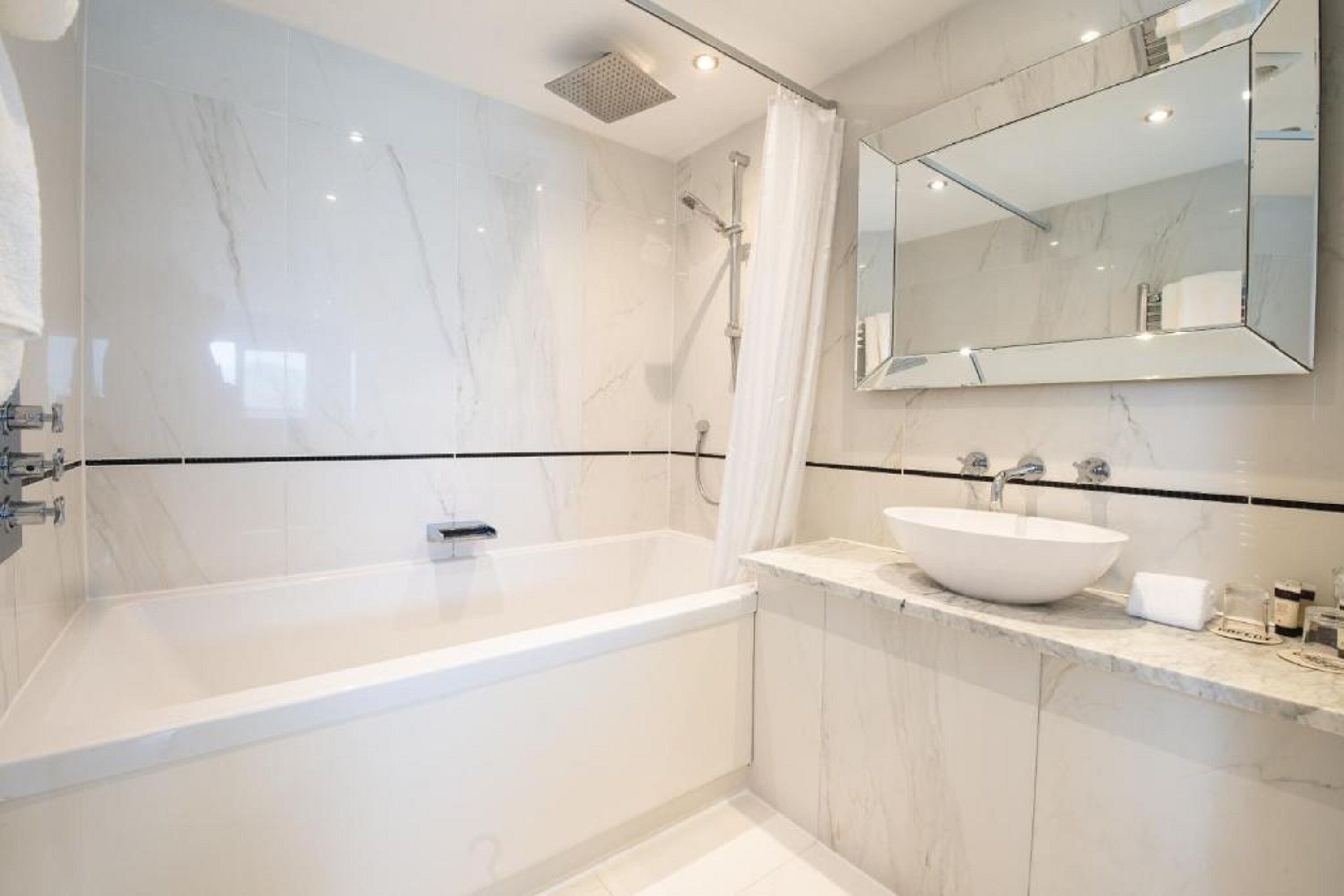 Ein modernes Badezimmer mit einer großzügigen Badewanne, einem weißen Waschbecken und einem großen Spiegel.