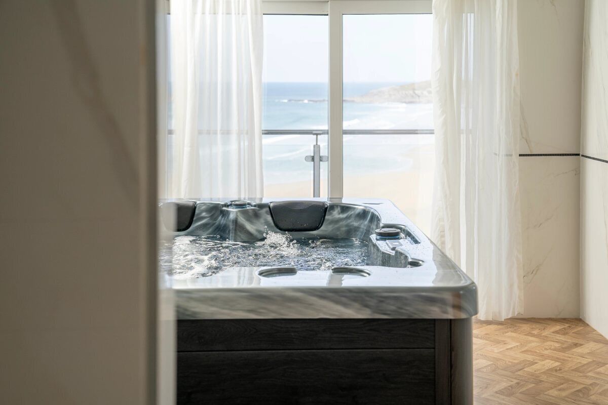 Un bain à remous avec vue sur l’océan, accessible par une porte vitrée.