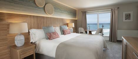 A hotel room with a large bed, a desk, and a view of the ocean.