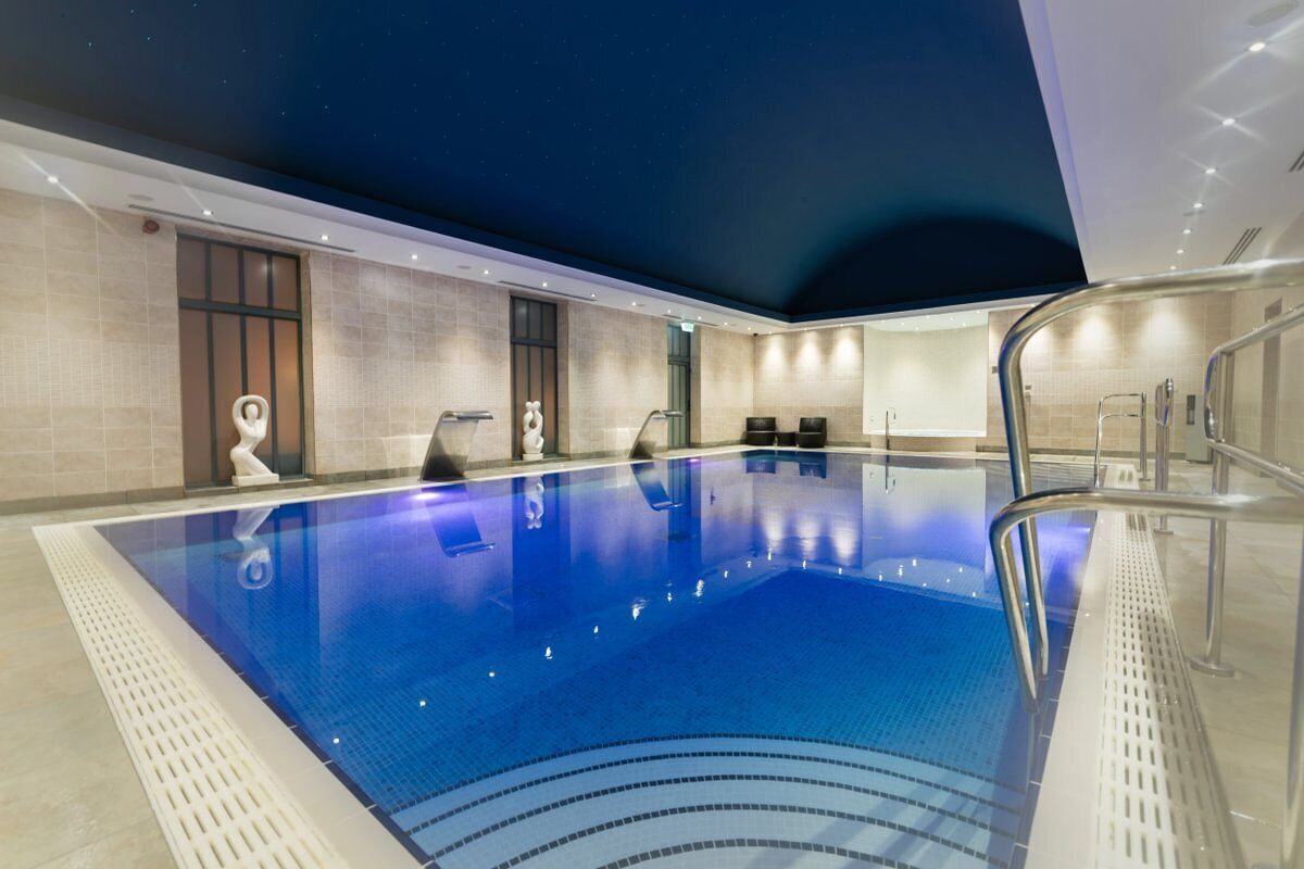 Una piscina interior con agua cristalina, suelo de baldosas y diseño moderno.