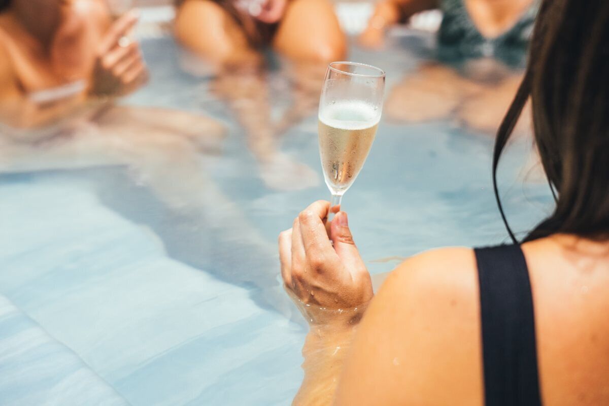 A person holding a glass of champagne in a pool.