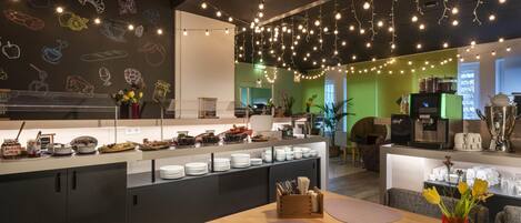 Una cafetería moderna con una barra larga, diversas opciones de comida y una pared decorada con ilustraciones de alimentos.