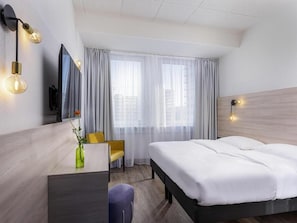 A hotel room with a bed, a desk, a chair, a TV, and a window with curtains. - St Christopher's Hotel Berlin - Alexanderplatz (Berlin)