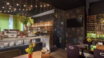 Ein Restaurant mit Barbereich, einem Selbstbedienungs-Pfannkuchenstand und einer Wand mit Illustrationen von Getränken.