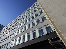 Un edificio de varias plantas con un diseño arquitectónico moderno, que presenta una cuadrícula de ventanas y una fachada plana.