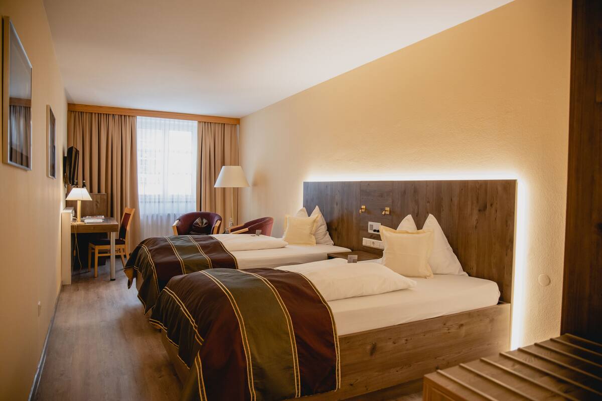 Ein Hotelzimmer mit zwei Betten, einem Schreibtisch und einem Stuhl.