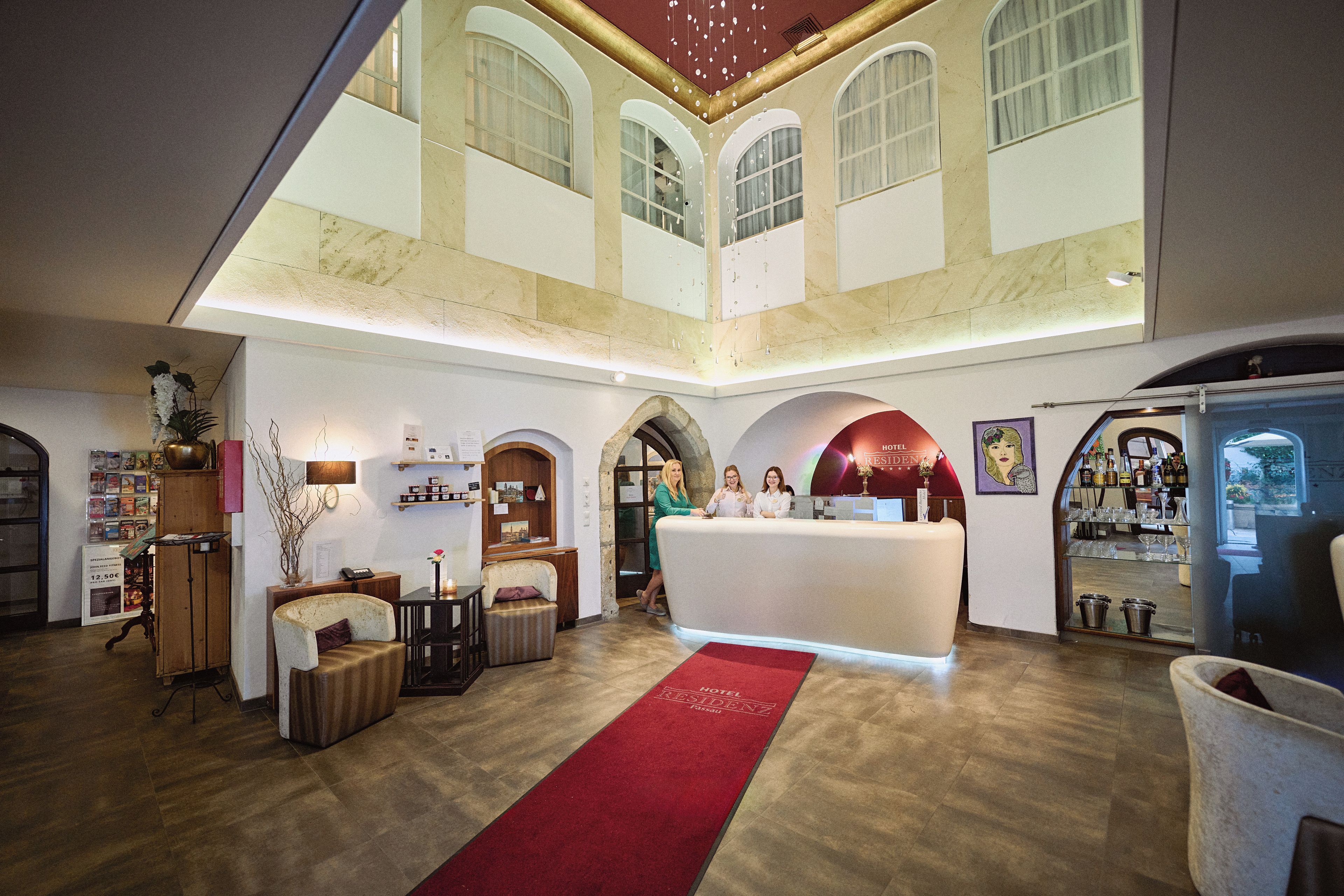 Un hall de hotel con alfombra roja, una recepción y un área de bar.