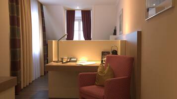 Ein Hotelzimmer mit Schreibtisch, Stuhl und einem Fenster mit Vorhängen.