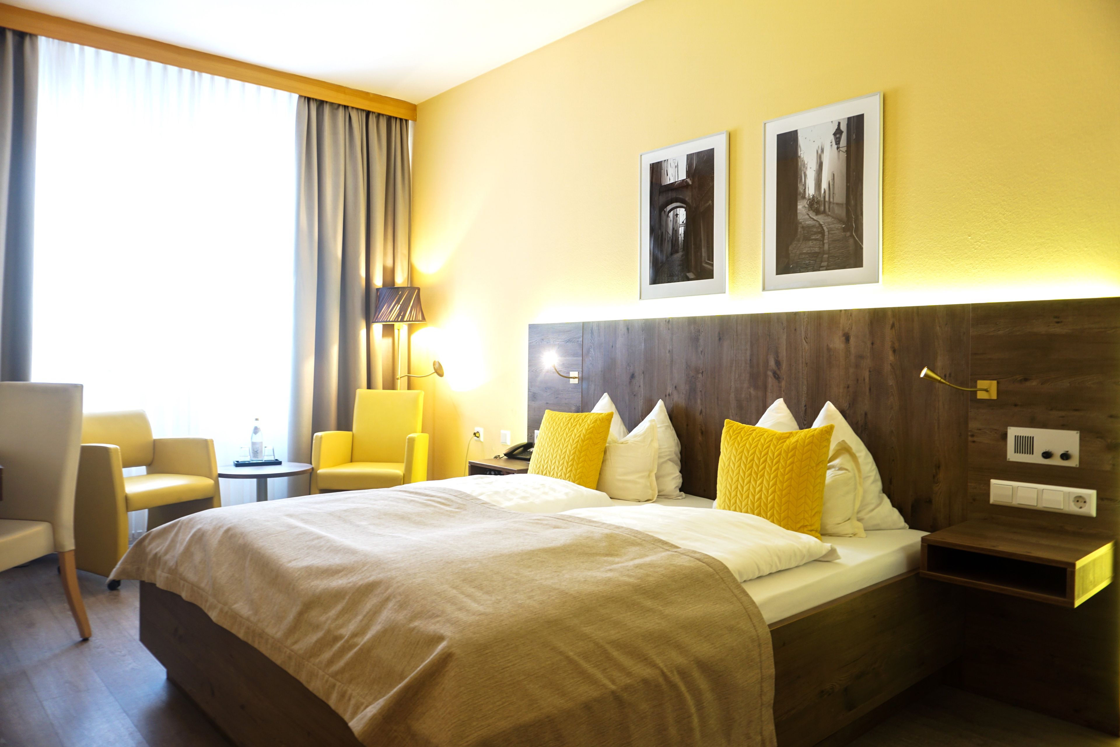 Une chambre d’hôtel avec un grand lit, deux tables de chevet, un bureau, une chaise et une lampe.