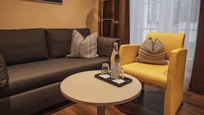 A modern living room with a grey sofa, a yellow armchair, a round coffee table, and a floor lamp. - Hotel Residenz Passau (Passau)