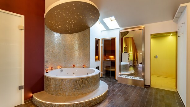 A modern bathroom with a circular jacuzzi, a skylight, and a yellow door. - Hotel Residenz Passau (Passau)