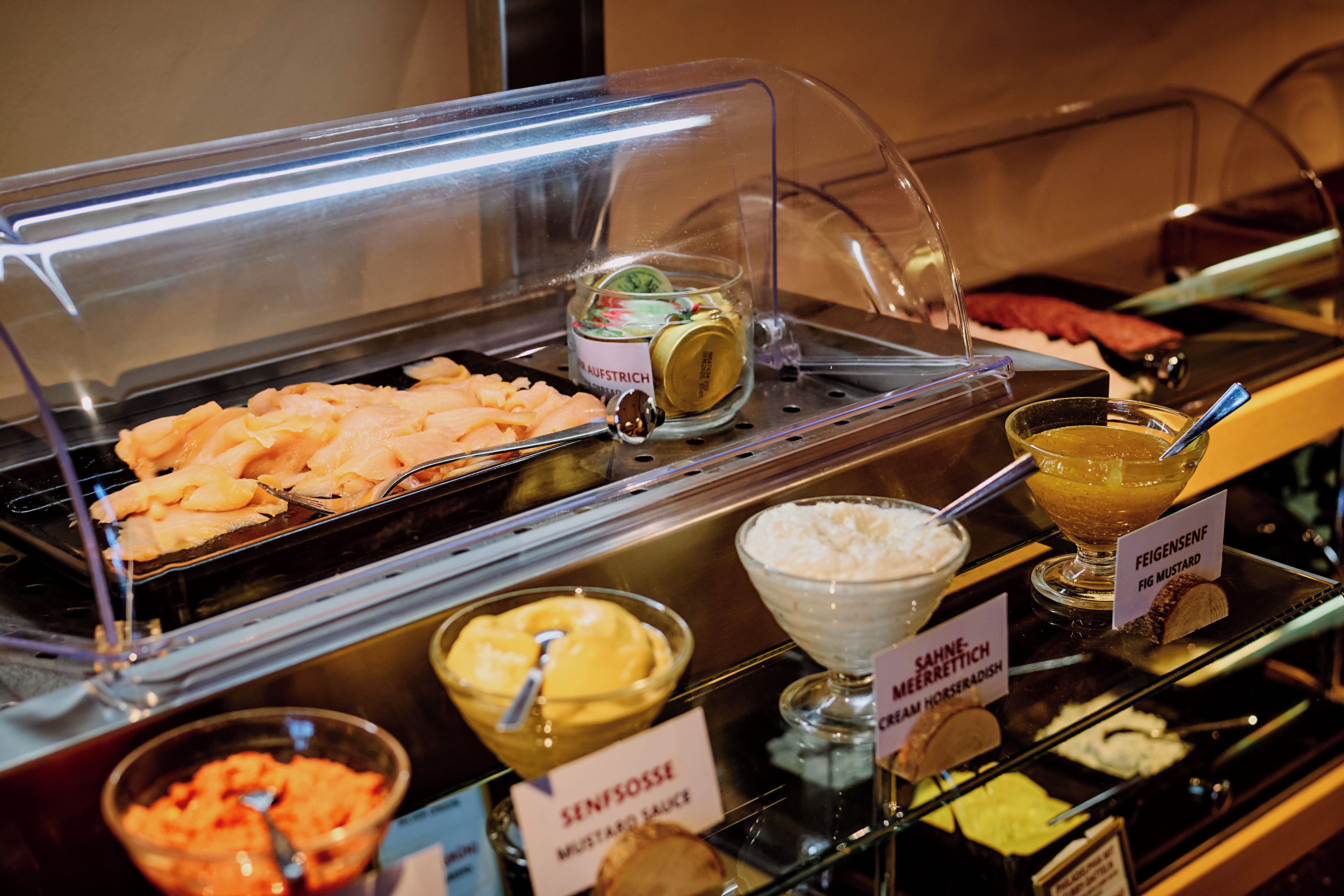 Ein reichhaltiges Buffet mit verschiedenen Speisen, darunter Fleisch, Soßen und Beilagen.