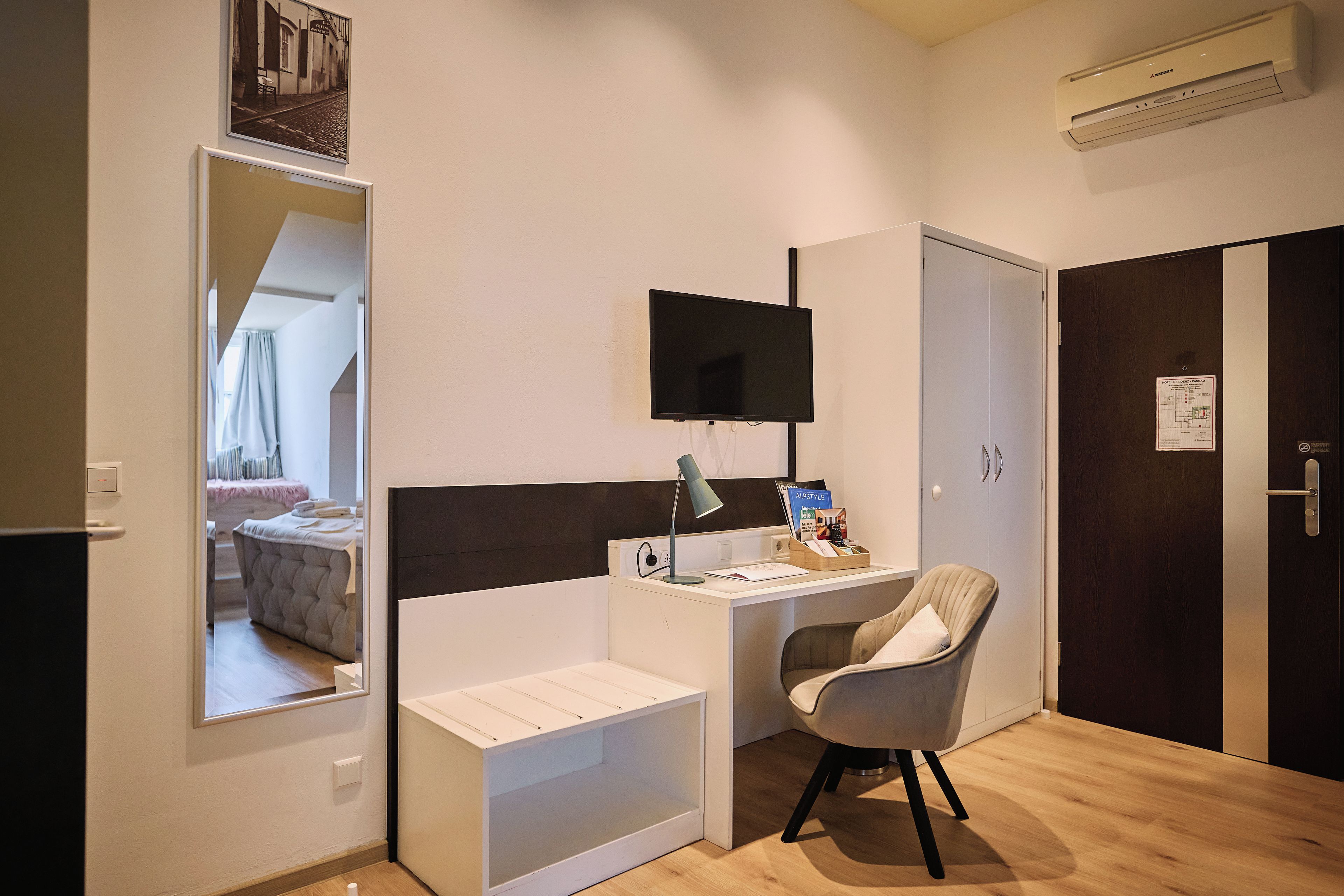 Habitación de hotel con escritorio, silla, televisor de pantalla plana y un espejo grande.