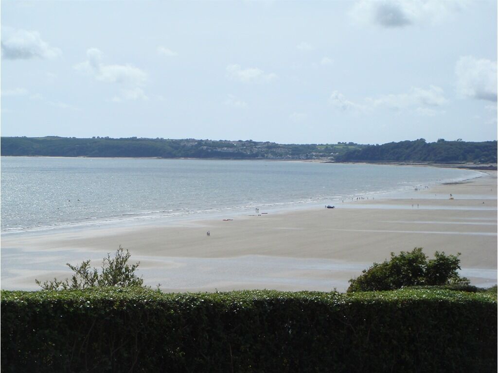 Ein Strand mit freiem Blick auf das Meer und hügelige Fernlandschaft.
