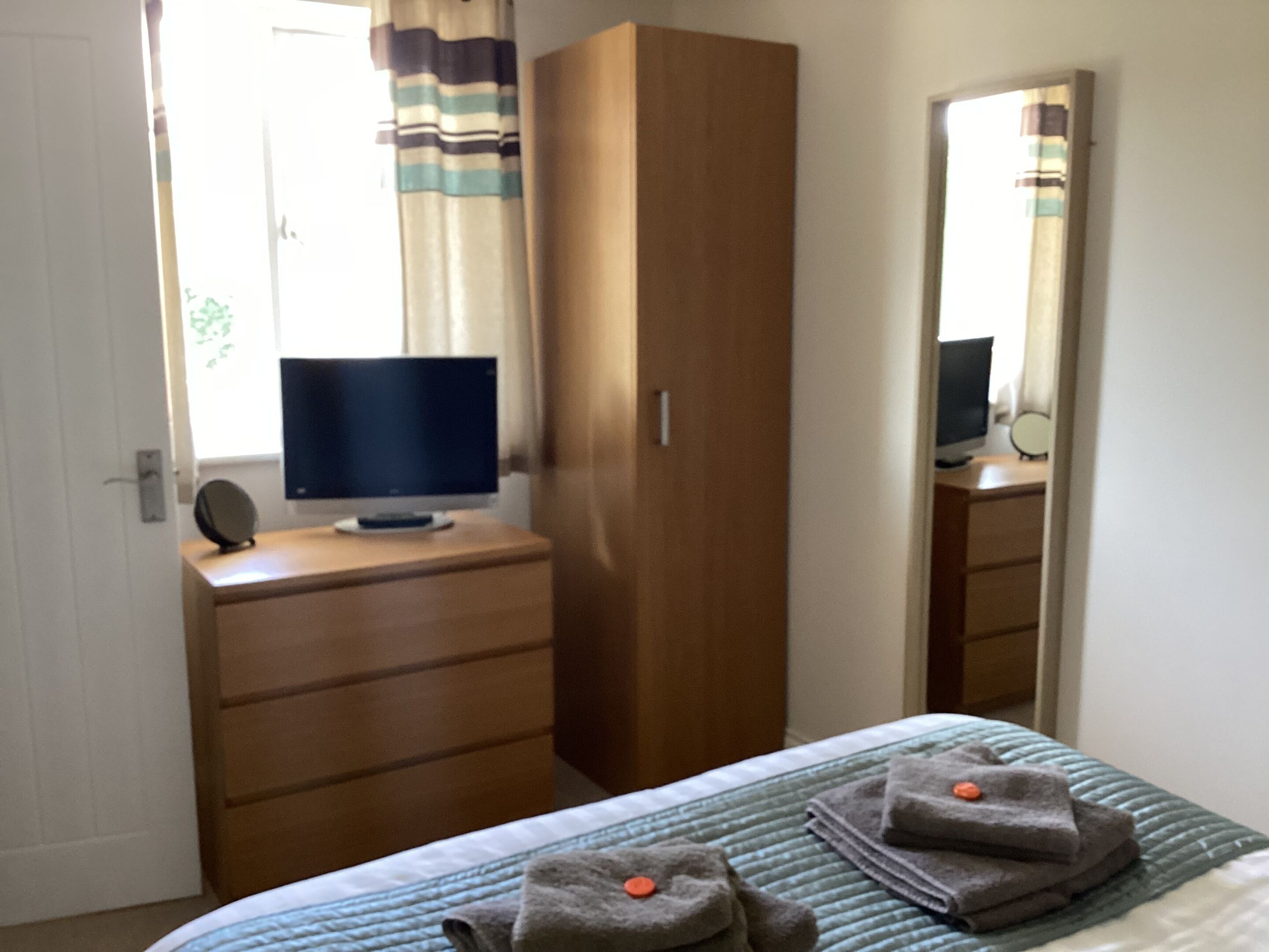 Een slaapkamer met een bed, een dressoir, een televisie en een kledingkast.
