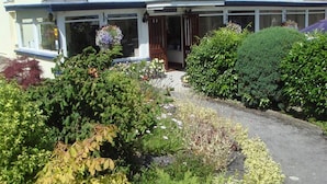 A two-story building with a covered entrance and a garden in front. - The Manian (Kilgetty)