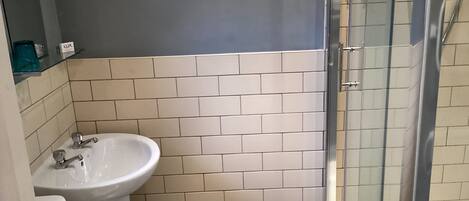 Ein Badezimmer mit Waschbecken, Toilette und einer Duschkabine aus Glas.