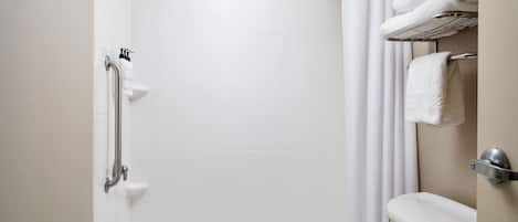Un baño con bañera, inodoro, cabezal de ducha y toallero.