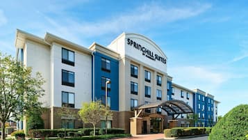A modern hotel with a prominent sign reading "Springhill Suites by Marriott." It features a multi-story building with a flat roof, large windows, and a covered entrance area.
